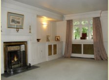 Painted panelled room with matching brass grilles to radiator covers and cupboard doors
